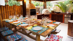 A wooden dining table set for a meal with multiple plates, glasses, and cutlery. - Casa do Mar Buzios (Búzios)