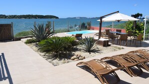 A poolside area with lounge chairs, a table, and a pergola with an umbrella. - Casa do Mar Buzios (Búzios)