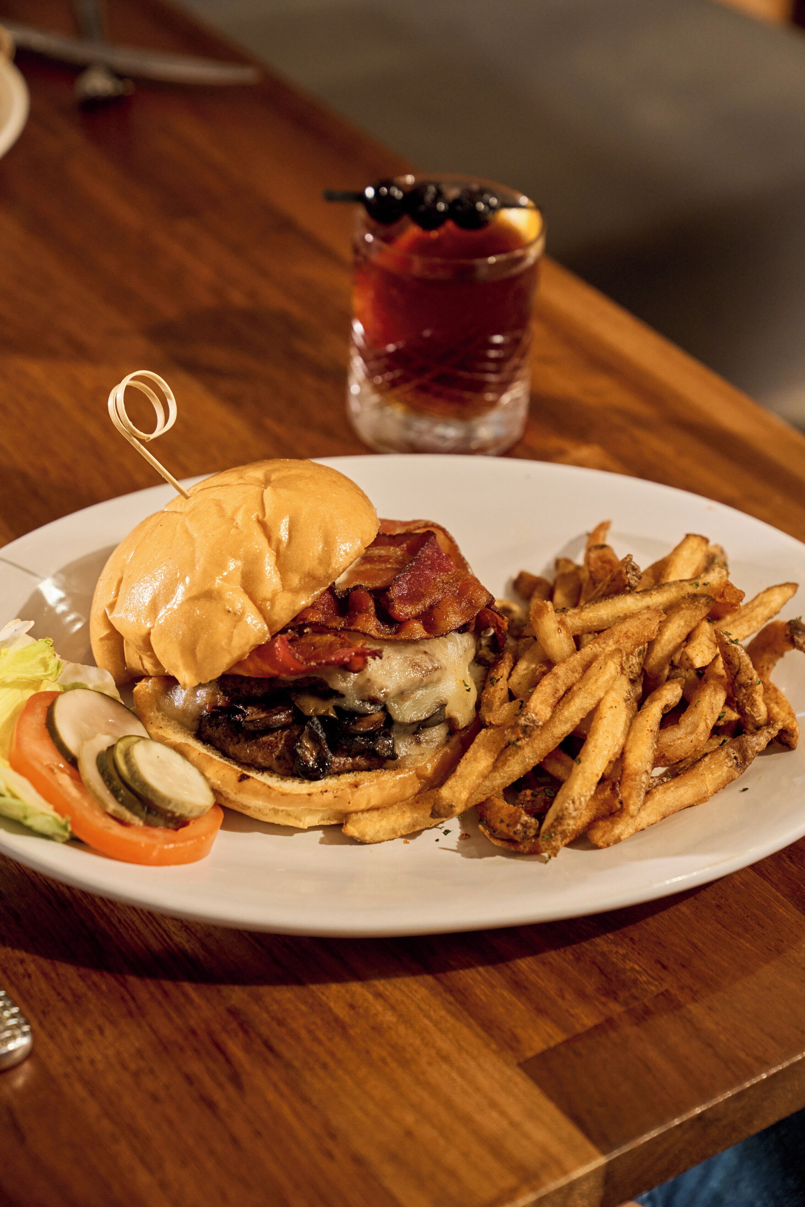 A plate with a burger, fries, and a drink.