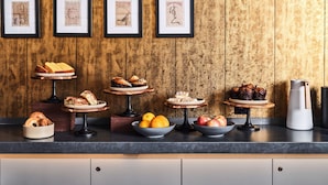 Una encimera de cocina con diversos productos horneados y frutas, una obra de arte en la pared y una cafetera.