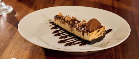 Een dessert op een bord met een lepel, een glas lichtkleurig drankje en een vork op een houten tafel.