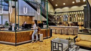 Un vestíbulo de hotel moderno con mostrador de recepción, zona de estar y una escalera.