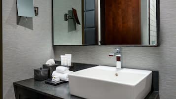 A modern bathroom with a large rectangular sink, a mirror, and a dark countertop.