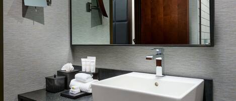 Un baño moderno con un lavamanos rectangular grande, un espejo y una encimera oscura.