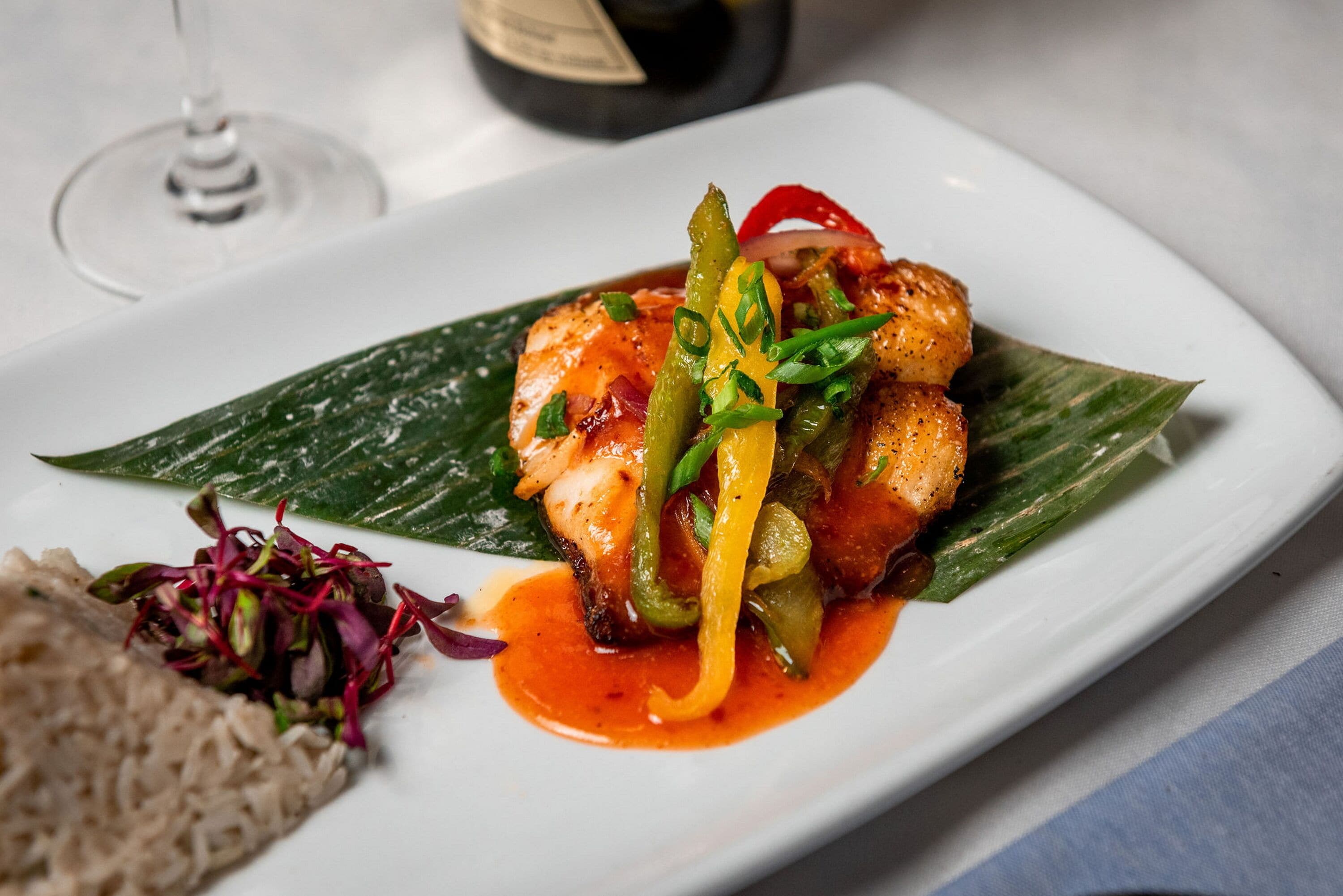 A plate of food with a side of rice and a glass of wine.