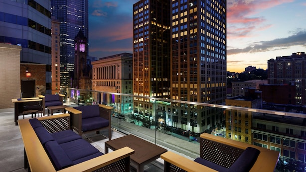 Un lounge en la azotea con asientos y vistas a la ciudad al atardecer.