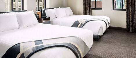 A hotel room with two beds, large windows, a carpeted floor, and a city view.