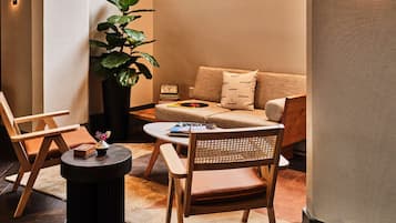 A modern living room with a sofa, two chairs, a coffee table, and a potted plant.