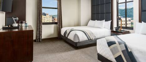 Habitación de hotel con cama, escritorio, televisor y ventana con vista a la ciudad.