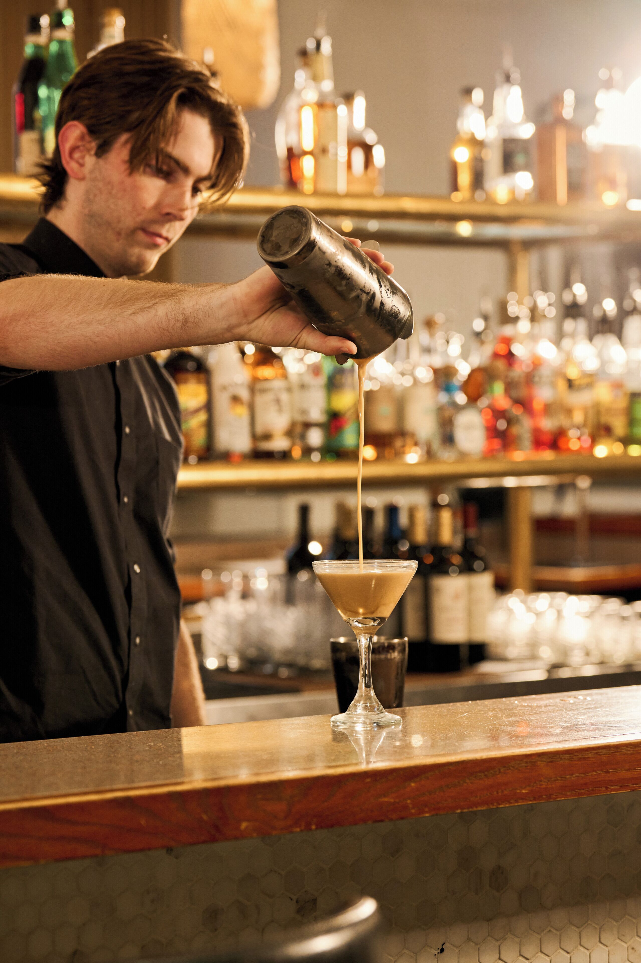 Eine Person gießt Flüssigkeit in ein Martini-Glas.