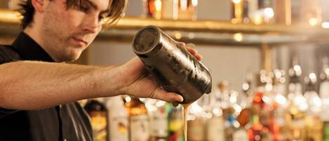A person pouring a liquid into a martini glass.