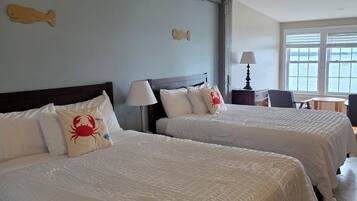 Habitación de hotel con dos camas, vista al mar y una decoración de pez de madera en la pared.