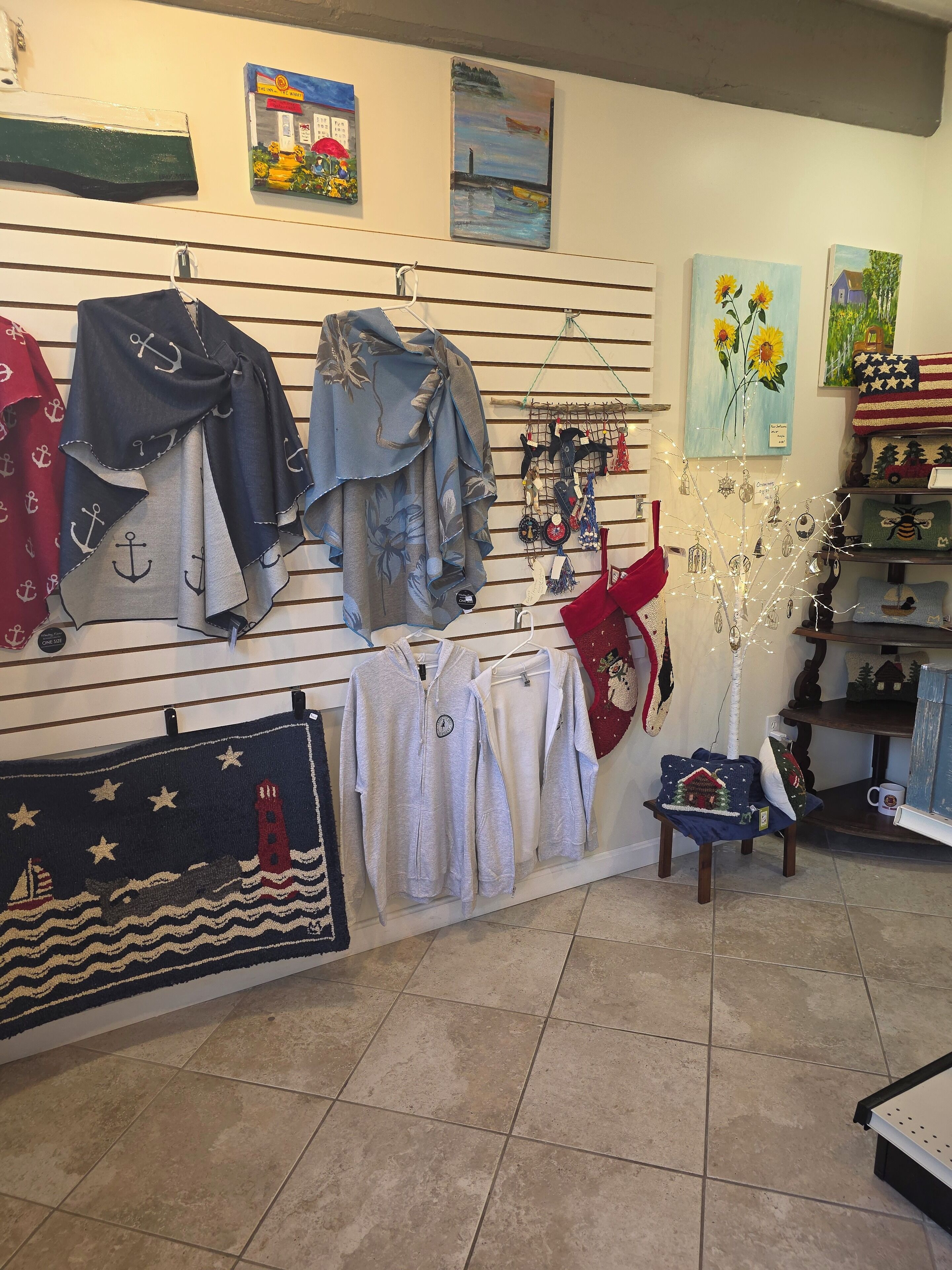 A room with a wall displaying various items including clothing, a small table with a decorative item, and a chair.