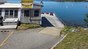 A waterfront restaurant with a dock extending into the water, a clear view of the lake, and a sign indicating it is a Fisherman's Wharf. - The Inn on the Wharf (Lubec)