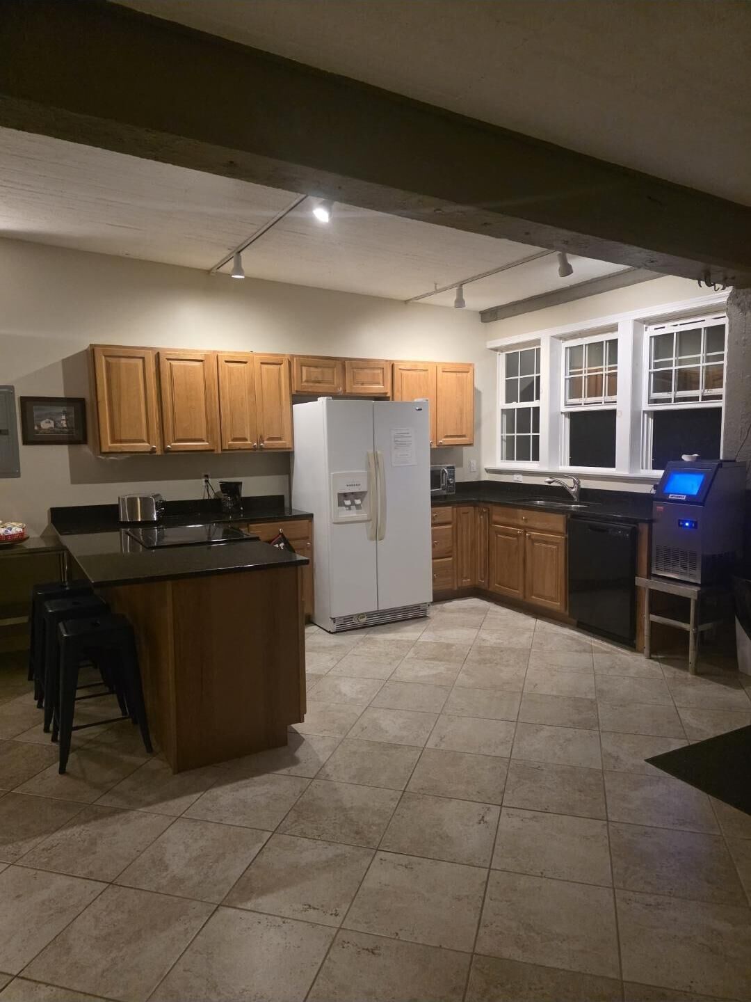 A kitchen with wooden cabinets, a refrigerator, a dishwasher, and a window.