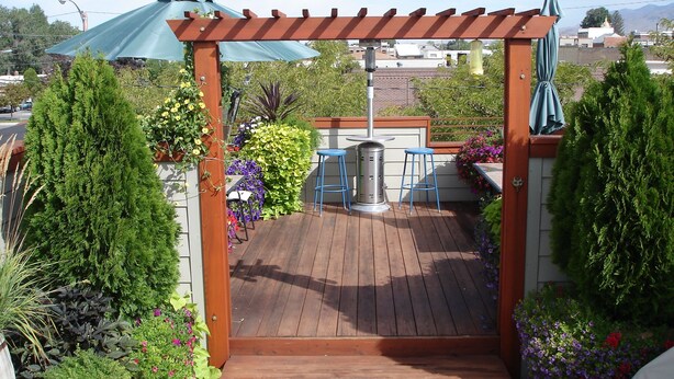 Une terrasse en bois avec une pergola, des chaises bleues et une table.