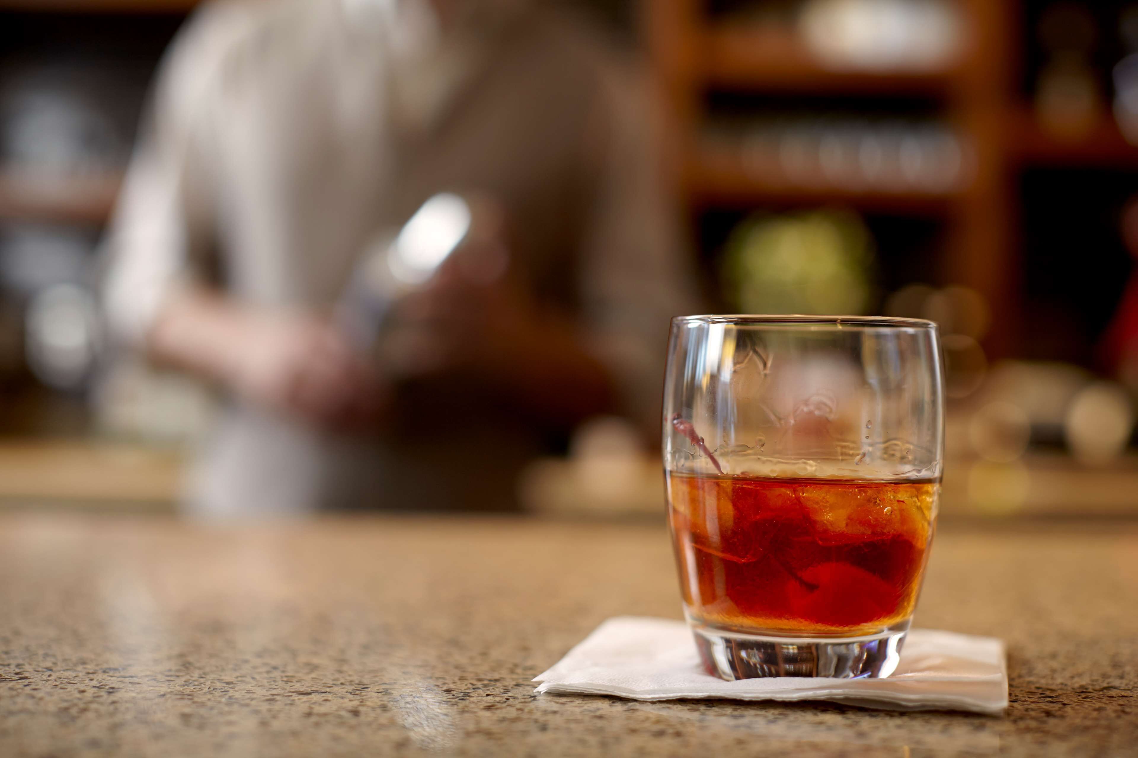 A glass of amber-colored beverage on a table with a napkin.