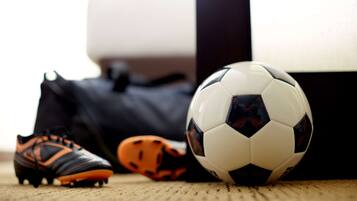 Un ballon de football, une paire de chaussures de foot et un gant de gardien de but, le tout posé sur un tapis.