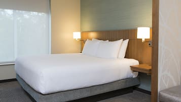 A neatly made bed with white linens, two bedside lamps, and a view of the outdoors through a window.