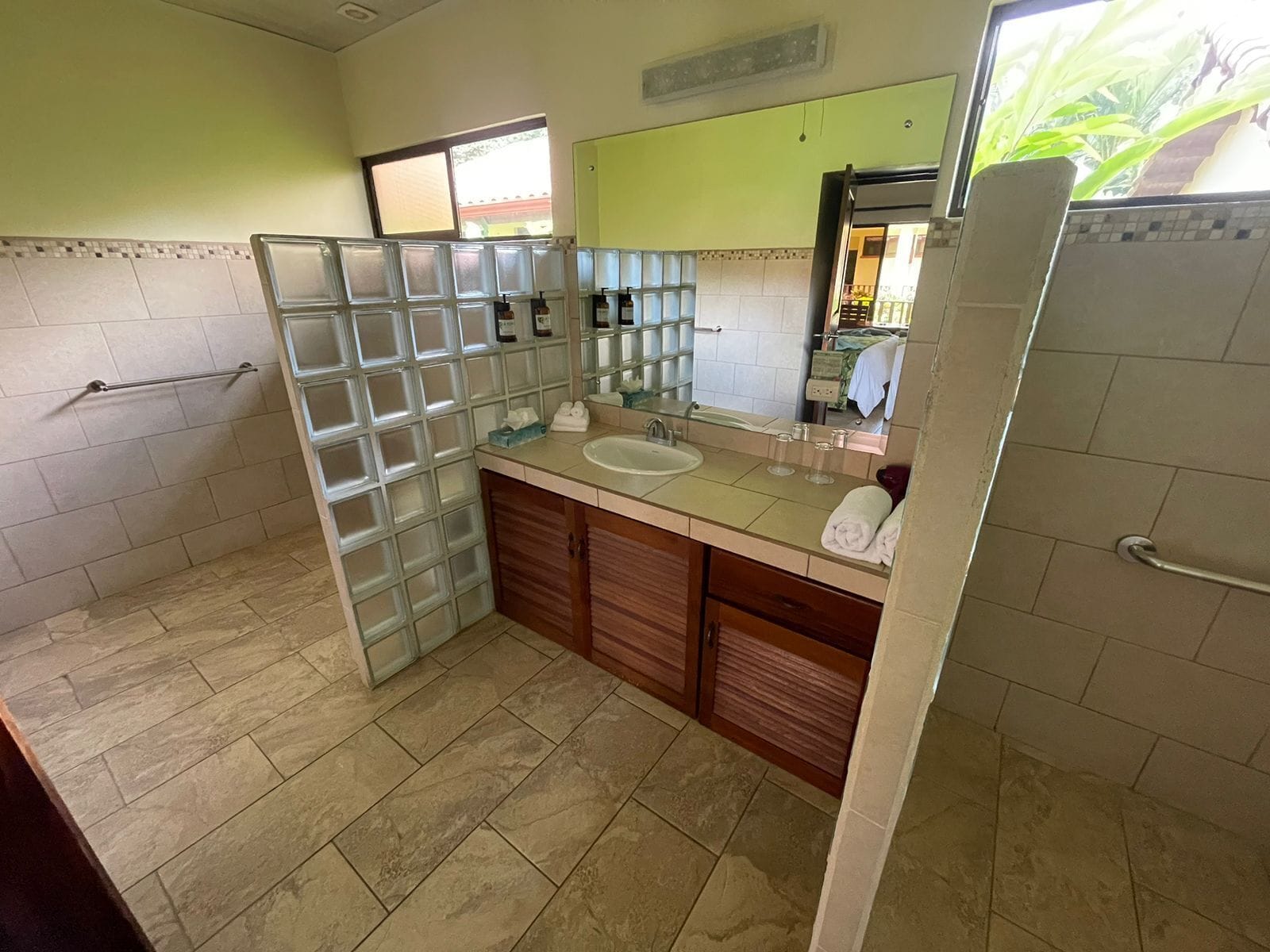 A bathroom with a glass shower enclosure, a sink with a mirror, and a towel rack.