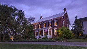 A brick house with a porch, American flags, and a well-maintained lawn. - Pheasant Field B&B (Carlisle)