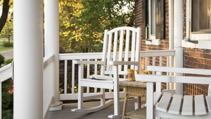 A white wooden porch with a rocking chair and a wicker table. - Pheasant Field B&B (Carlisle)
