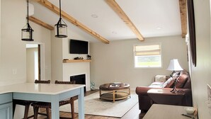 A cozy living room with a fireplace, a dining area with a table and chairs, and a sofa with a lamp. - Pheasant Field B&B (Carlisle)