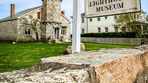 An Old Lighthouse Museum sign in front of a stone building with a lighthouse tower. - The Inn at Stonington (Stonington)