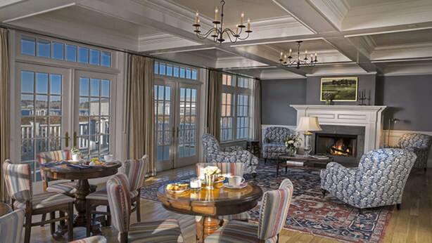 A spacious living room with a fireplace, large windows, and a chandelier. - The Inn at Stonington (Stonington)