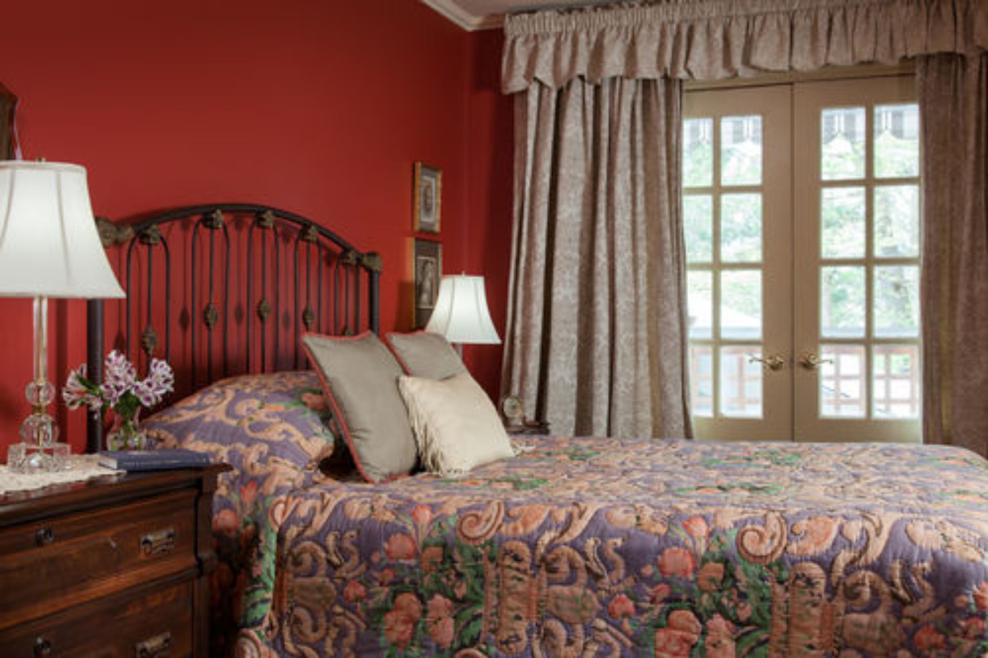 Un dormitorio con una cama grande, dos lámparas de noche, un aparador y una ventana con cortinas.