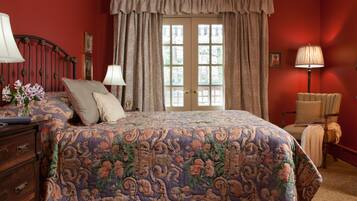A bedroom with a floral bedspread, a dresser, a chair, and a lamp.