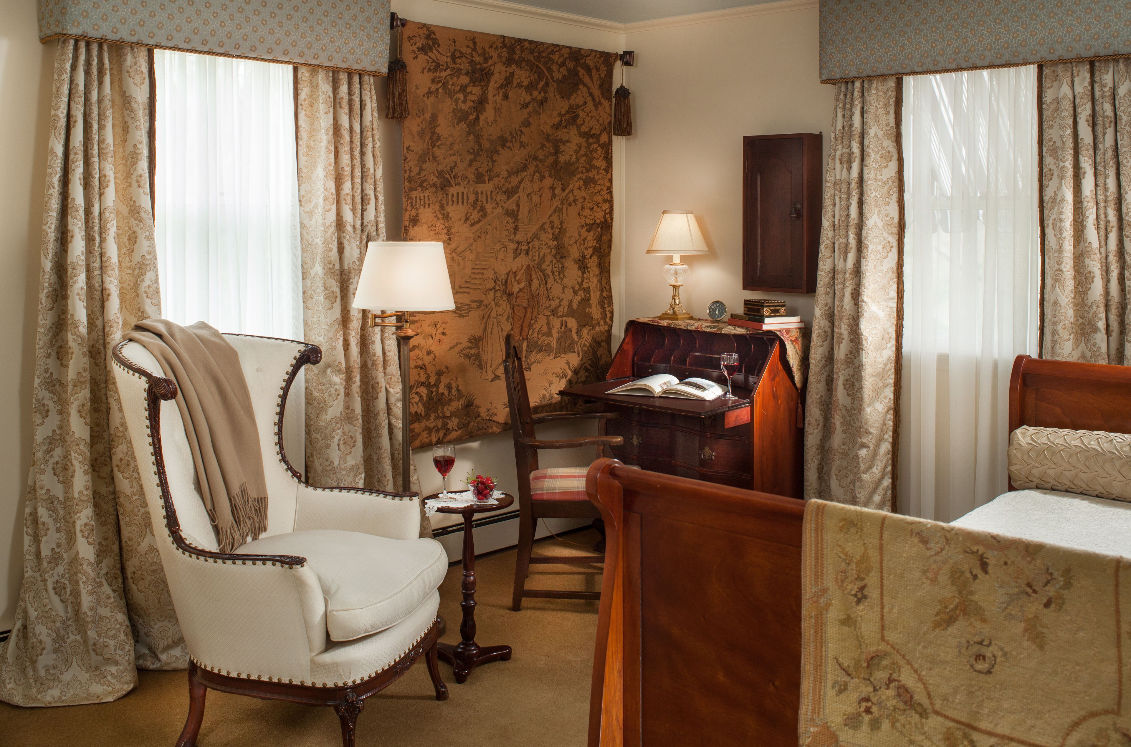 Una habitación con una cama, una silla, un escritorio con lámpara y una estantería.