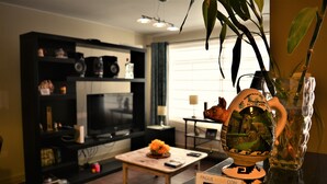Un salon avec un téléviseur, une table basse ornée d’un arrangement floral, un globe terrestre et un vase avec une plante.