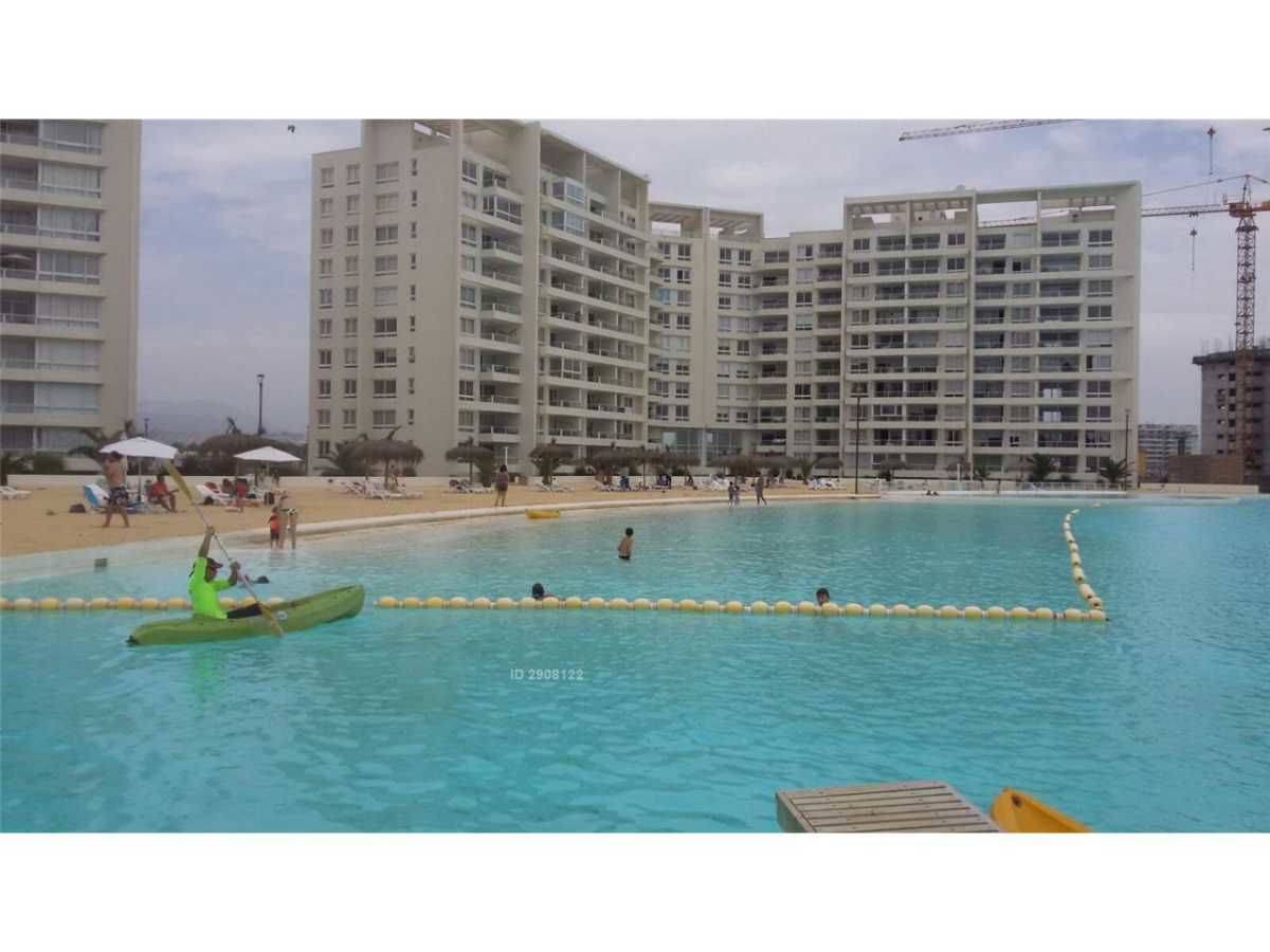 A swimming pool with a kayaker, surrounded by high-rise buildings and a beach.