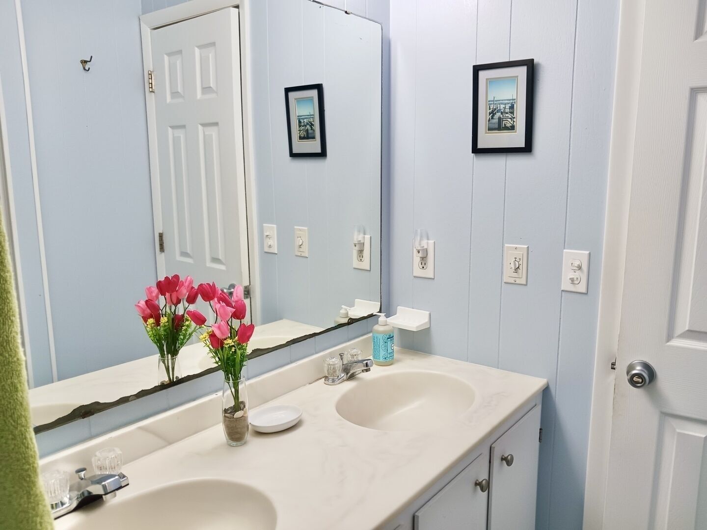 A bathroom with two sinks, a mirror, and a door.