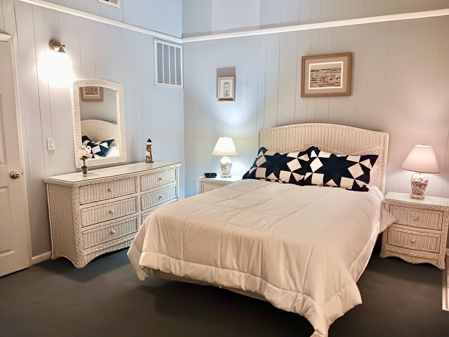 Un dormitorio con una cama grande, un aparador, un espejo y una mesita de noche con lámpara.
