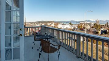 A balcony with a table and chairs, overlooking a town and mountains.