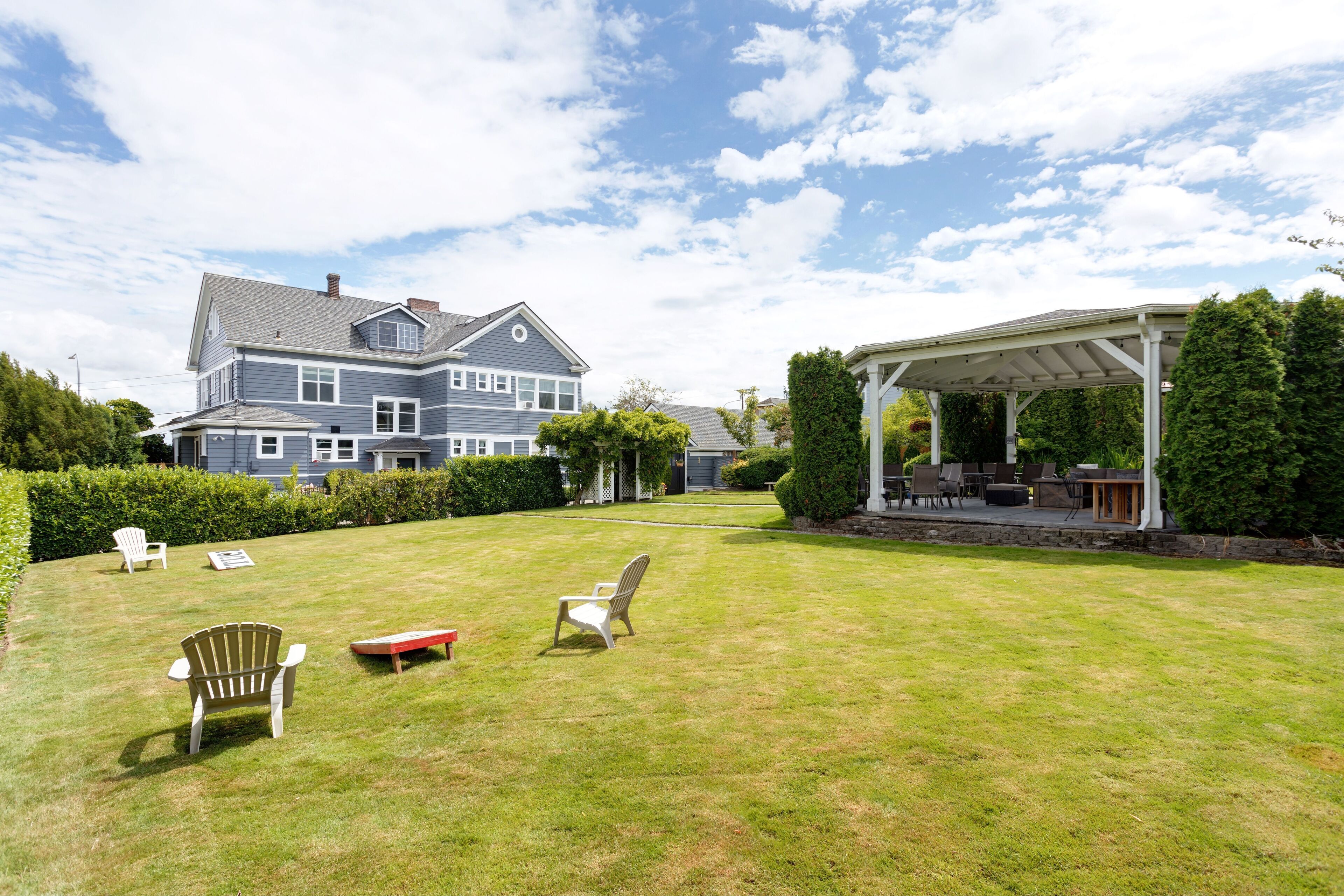 A large house with a covered patio and a well-maintained lawn with outdoor furniture.