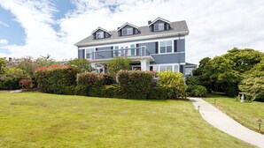 A two-story house with a front porch, a covered walkway, and a well-maintained lawn. - Nantucket Inn (Anacortes)