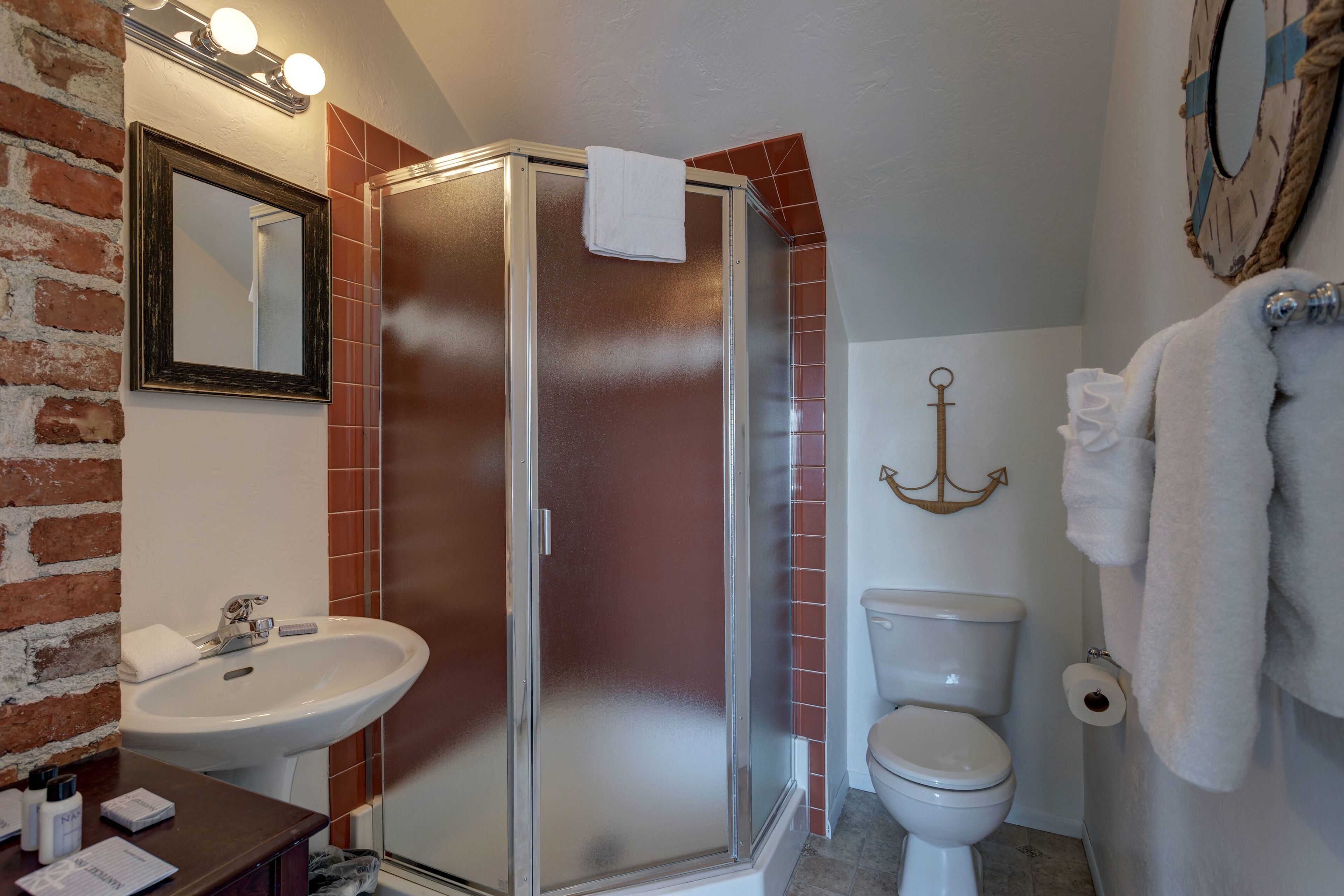 A bathroom with a shower, sink, toilet, and a mirror.