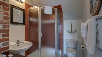 A bathroom with a shower, sink, toilet, and a mirror.