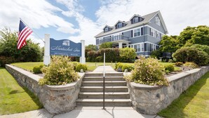 A hotel entrance with a sign, steps, and a flag. - Nantucket Inn (Anacortes)