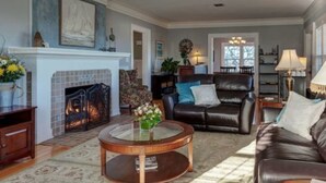 A living room with a fireplace, leather sofa, and a coffee table. - Nantucket Inn (Anacortes)