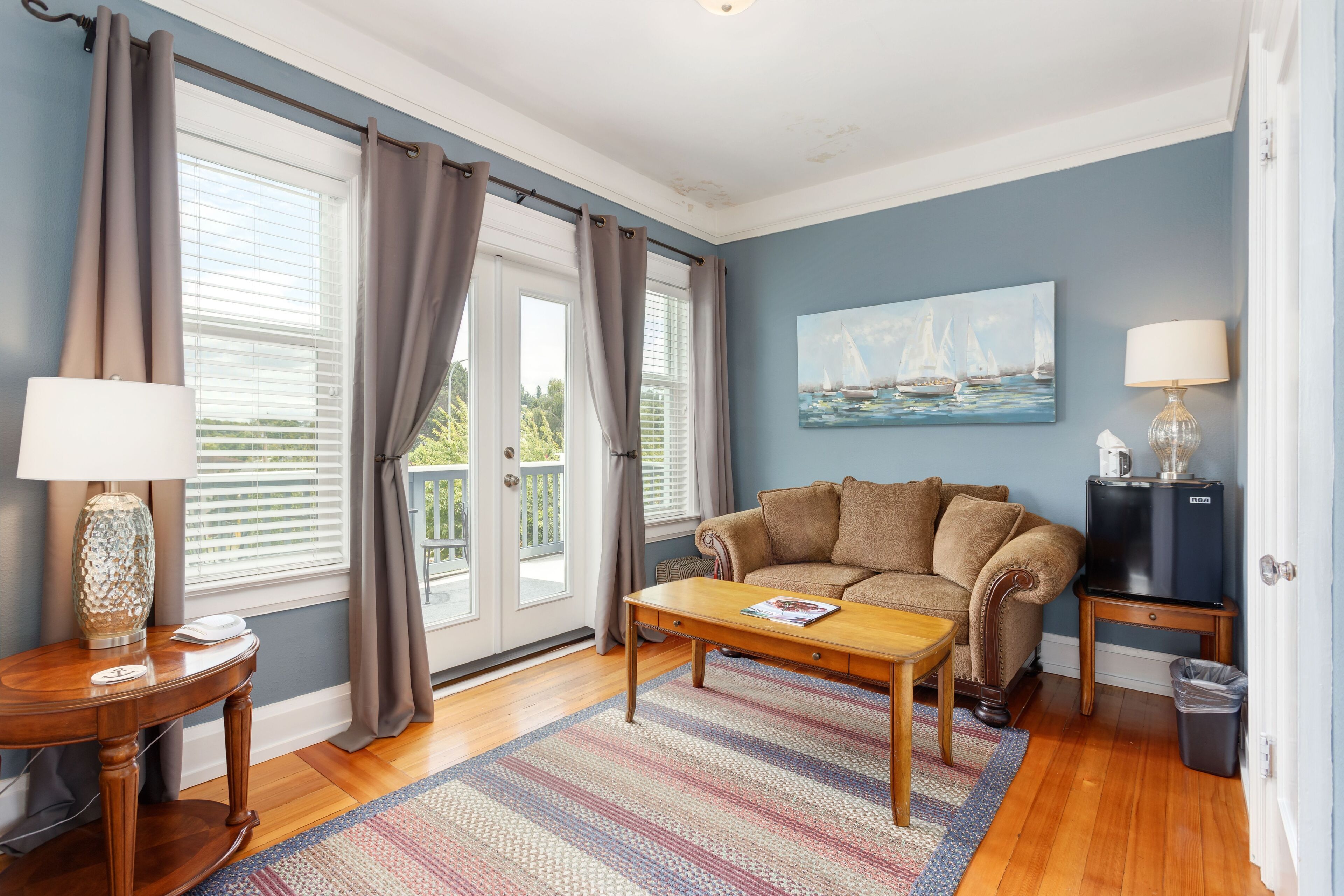 A living room with a sofa, coffee table, and a painting on the wall.