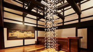 A wooden interior with a hanging light installation, a framed painting on the wall, and a wooden reception desk. - Hoshino Resorts KAI Kaga (Kaga)
