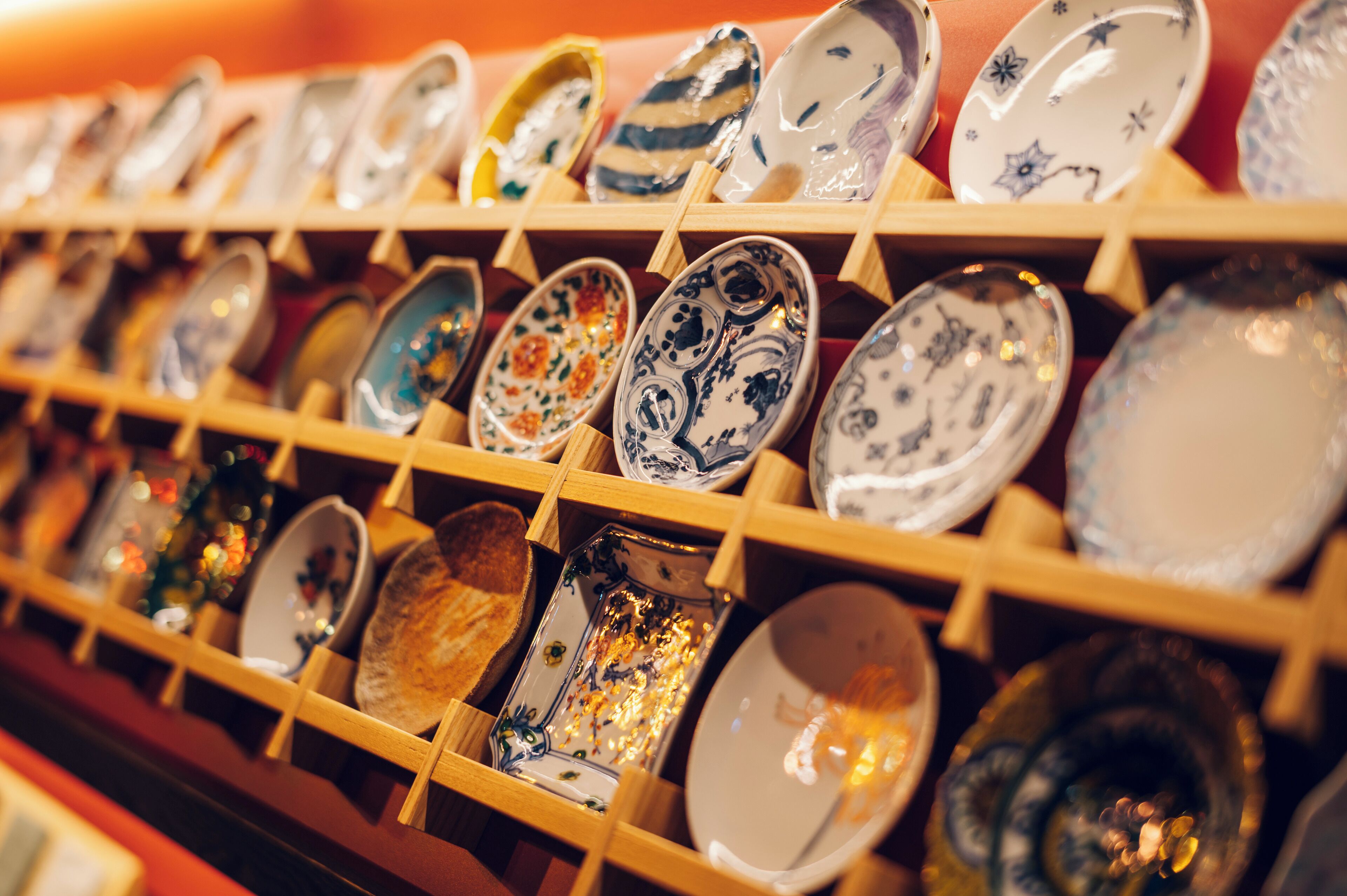 A display of various ceramic plates and bowls on wooden shelves.