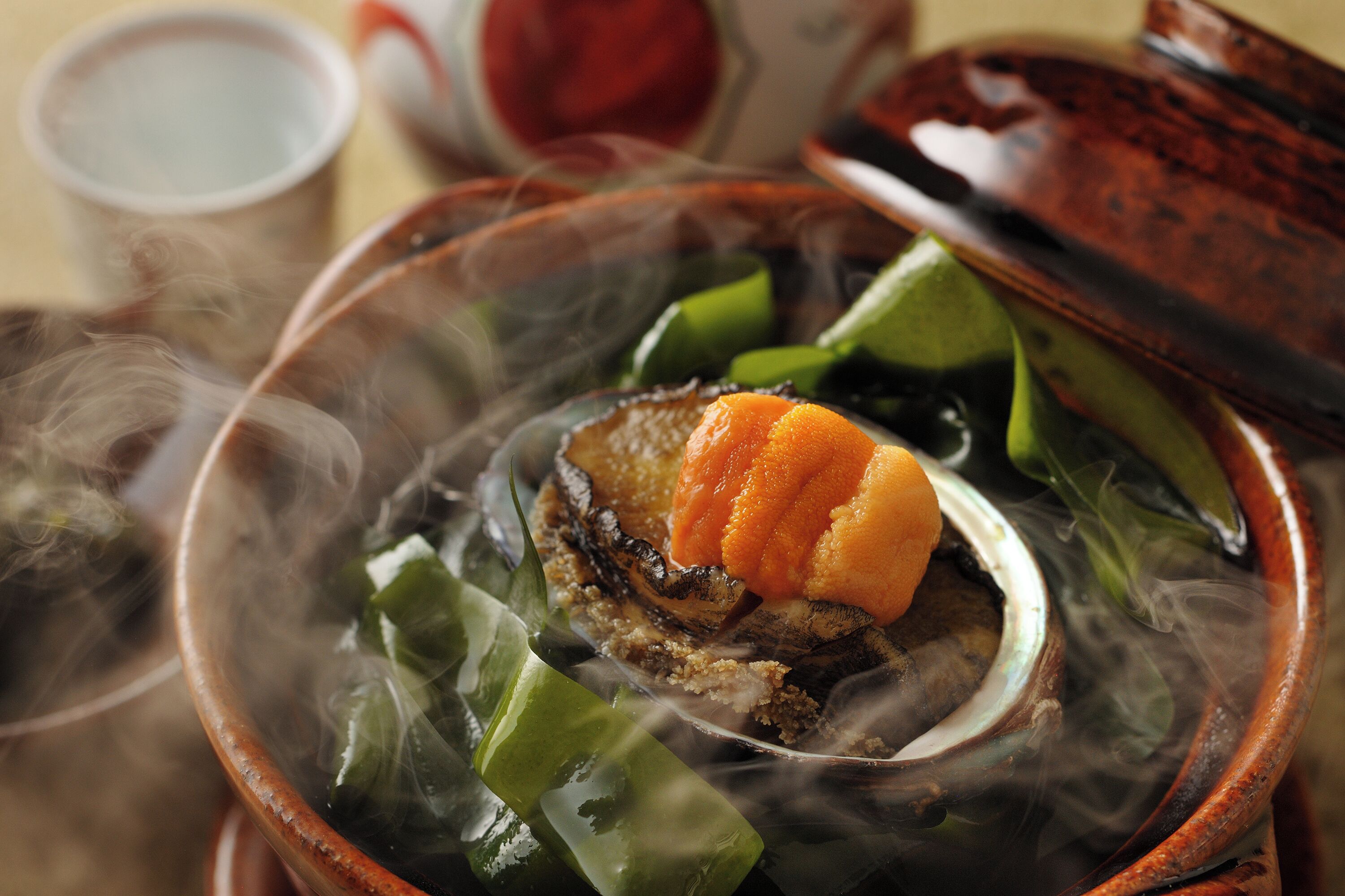 Uma tigela com comida, um pedaço de carne, legumes verdes e uma fatia de laranja.