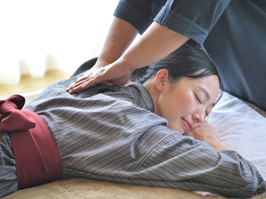 Een persoon ligt op een massagetafel en ontvangt een rugmassage.