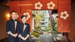 A couple standing in front of a traditional Japanese-style backdrop with a garden view. - Hoshino Resorts KAI Kaga (Kaga)