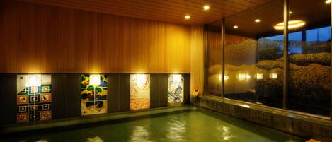 A swimming pool with wooden paneling and tiled artwork on the walls.